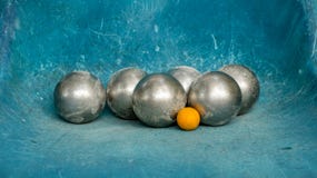 Bolas brillantes de Petanque del metal y bola de madera anaranjada en trullo azul imagenes de archivo Bolas brillantes de Petanque del metal y bola de madera anaranjada en trullo azul imagenes de archivo