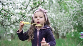 Bolhas de sab?o de sopro da menina feliz no jardim da mola Movimento lento filme Bolhas de sab?o de sopro da menina feliz no jardim da mola Movimento lento filme