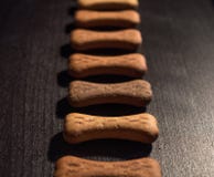 Bone shaped dog cookies or treats, on dark wood background royalty free stock image Bone shaped dog cookies or treats, on dark wood background royalty free stock image
