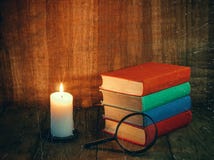 Books and a white candle on a wooden table. Reading by candlelight. Vintage composition. stock image Books and a white candle on a wooden table. Reading by candlelight. Vintage composition. stock image