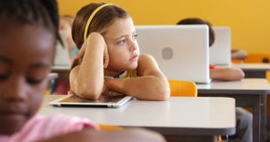 Bored girl sitting at desk in classroom