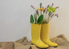 Botas de chuva com as flores do equipamento e da mola de jardinagem no fundo do eco do pano de saco foto de stock Botas de chuva com as flores do equipamento e da mola de jardinagem no fundo do eco do pano de saco foto de stock