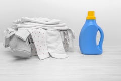 Bottiglia con il detersivo liquido contro lo sfondo del canestro con i vestiti del bambino fotografie stock Bottiglia con il detersivo liquido contro lo sfondo del canestro con i vestiti del bambino fotografie stock