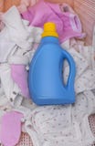 Bottiglia del detersivo di lavanderia nel canestro con i vestiti sporchi del bambino immagine stock libera da diritti Bottiglia del detersivo di lavanderia nel canestro con i vestiti sporchi del bambino immagine stock libera da diritti