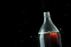 Bottiglia della bibita con la spruzzata del ghiaccio su fondo scuro La bibita imbottiglia il concetto del partito della celebrazi fotografie stock libere da diritti Bottiglia della bibita con la spruzzata del ghiaccio su fondo scuro La bibita imbottiglia il concetto del partito della celebrazi fotografie stock libere da diritti