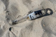 Bottiglia e cappuccio vuoti di Corona Extra sulla spiaggia fotografia stock libera da diritti Bottiglia e cappuccio vuoti di Corona Extra sulla spiaggia fotografia stock libera da diritti