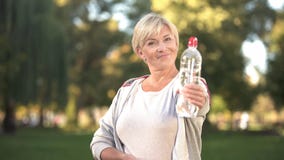 Bottiglia sorridente di rappresentazione della donna di acqua frizzante prima della macchina fotografica, stile di vita sano immagine stock libera da diritti Bottiglia sorridente di rappresentazione della donna di acqua frizzante prima della macchina fotografica, stile di vita sano immagine stock libera da diritti