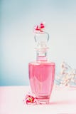 Bottle of lotion or perfume with pink flowers , natural cosmetic product or beauty concept on pastel blue background stock image Bottle of lotion or perfume with pink flowers , natural cosmetic product or beauty concept on pastel blue background stock image