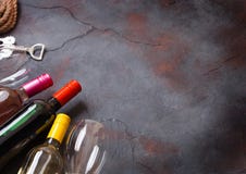 Bottles of red white and pink rose wine with glasses and corkscrew opener on stone kitchen table background. Top view. Space for t royalty free stock image Bottles of red white and pink rose wine with glasses and corkscrew opener on stone kitchen table background. Top view. Space for t royalty free stock image