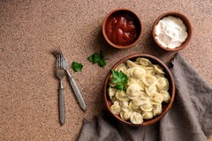 Boulettes russes de viande de pelmeni de nourriture avec la sauce de crème sure et tomate sur un dessus de table en pierre brun V photos stock Boulettes russes de viande de pelmeni de nourriture avec la sauce de crème sure et tomate sur un dessus de table en pierre brun V photos stock