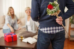 Bouquet de participation de jeune homme des fleurs derrière le dos pour sa mère photos stock Bouquet de participation de jeune homme des fleurs derrière le dos pour sa mère photos stock