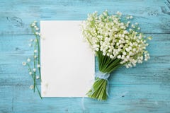 Bouquet du muguet de fleurs et de feuille de papier vide sur la table rustique de turquoise d'en haut, belle carte de vintage, vu Photographie stock libre de droits Bouquet du muguet de fleurs et de feuille de papier vide sur la table rustique de turquoise d'en haut, belle carte de vintage, vu Photographie stock libre de droits