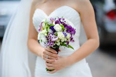 Bouquet nuptiale des fleurs pourpres et blanches dans des mains de la jeune mariée photos libres de droits Bouquet nuptiale des fleurs pourpres et blanches dans des mains de la jeune mariée photos libres de droits