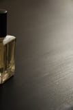 Bouteille de parfum d'or sur une table noire photos libres de droits Bouteille de parfum d'or sur une table noire photos libres de droits