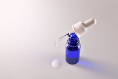 Bouteille en verre bleue et compte-gouttes sur blanc sup?rieur ?lev?s images libres de droits Bouteille en verre bleue et compte-gouttes sur blanc sup?rieur ?lev?s images libres de droits