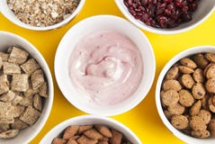 Bowls of whole grain muesli, dried fruits, granola and oatmeals arranged in circle. Isolated on yellow background. Top view. stock photos Bowls of whole grain muesli, dried fruits, granola and oatmeals arranged in circle. Isolated on yellow background. Top view. stock photos