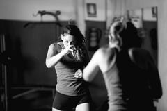 Boxeador de sexo femenino profesional que se resuelve mientras que mira en espejo foto de archivo libre de regalías Boxeador de sexo femenino profesional que se resuelve mientras que mira en espejo foto de archivo libre de regalías