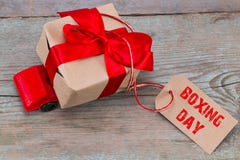 The BOXING DAY concept. Red toy car delivering gifts box with ta stock photo The BOXING DAY concept. Red toy car delivering gifts box with ta stock photo