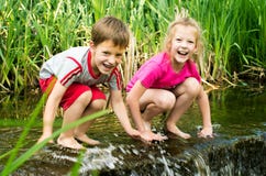 Boy And Girl Sitting In Water Near Small Waterfall Stock Images