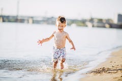 Boy child playing makes splashes, beats hands on the water in the river at sunset royalty free stock image Boy child playing makes splashes, beats hands on the water in the river at sunset royalty free stock image