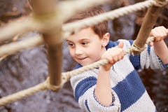 Boy Crossing Stream On Rope Bridge At Activity Centre Royalty Free Stock Photography Boy Crossing Stream On Rope Bridge At Activity Centre Royalty Free Stock Photography