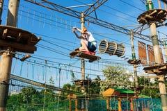 Boy in forest adventure park. Kid in orange helmet and white t shirt climbs on high rope trail. Climbing outdoor stock images Boy in forest adventure park. Kid in orange helmet and white t shirt climbs on high rope trail. Climbing outdoor stock images