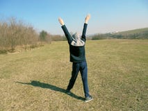 Boy with hands up stands in the meadow stock photo Boy with hands up stands in the meadow stock photo