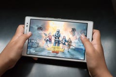 Boy holding a digital tablet playing online mobile game called PUBG