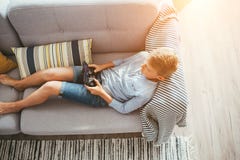 Boy laying on sofa plays with electronic devices - gamepad connected with smartphone stock image Boy laying on sofa plays with electronic devices - gamepad connected with smartphone stock image