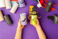 Boy Makes Halloween Toys From Paper. Toilet Roll Tube By Hands. Creative DIY For Kids On Traditional Purple Backgrpund. Home Decor Stock Photo Boy Makes Halloween Toys From Paper. Toilet Roll Tube By Hands. Creative DIY For Kids On Traditional Purple Backgrpund. Home Decor Stock Photo