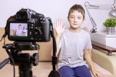 A boy, male child video blogger recording vlog or podcast, streaming online. Blurred camera on tripod in front stock photos A boy, male child video blogger recording vlog or podcast, streaming online. Blurred camera on tripod in front stock photos