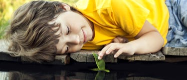 Boy play with autumn leaf ship in water, children in park play w stock photos Boy play with autumn leaf ship in water, children in park play w stock photos