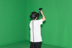 A boy is playing a virtual reality game in front of a green wall Stock Image A boy is playing a virtual reality game in front of a green wall Stock Image