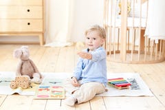 A boy plays with wooden toys and shows the number 2. Educational wooden toys for a child. Portrait of a boy sitting on the floor i stock photos A boy plays with wooden toys and shows the number 2. Educational wooden toys for a child. Portrait of a boy sitting on the floor i stock photos