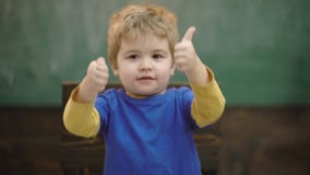 Boy raises his thumb up against background of a green school board. Selective focus. Back to school. Learning concept