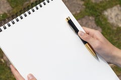 Boy`s hand with a pencil over an open notepad in the park stock image Boy`s hand with a pencil over an open notepad in the park stock image