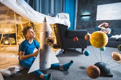 Boy sitting in blanket fort with toy rocket and solar system model royalty free stock photo Boy sitting in blanket fort with toy rocket and solar system model royalty free stock photo