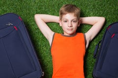 Boy and siutcases th lying on green grass close up Stock Photos Boy and siutcases th lying on green grass close up Stock Photos