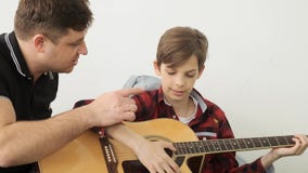 Boy spends the great leisure learning how to play guitar with his father slow motion