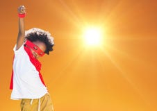 Boy in superhero costume pretending to fly against orange background