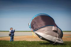 A boy with a tent in the field. Very strong wind, the tent flies away. Flying tent Summer, windy stock images A boy with a tent in the field. Very strong wind, the tent flies away. Flying tent Summer, windy stock images