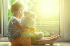 Boy of two years sitting by the window and hugs a toy Bunny. rainy weather, waiting for dad to come home from work stock photo Boy of two years sitting by the window and hugs a toy Bunny. rainy weather, waiting for dad to come home from work stock photo