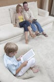 Boy Using Digital Tablet With Parents Watching TV Royalty Free Stock Image Boy Using Digital Tablet With Parents Watching TV Royalty Free Stock Image