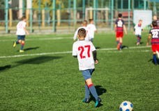 Boys in red white sportswear running on soccer field. Young footballers dribble and kick football ball in game. Training stock photos Boys in red white sportswear running on soccer field. Young footballers dribble and kick football ball in game. Training stock photos