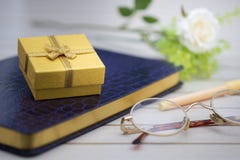 Boîte-cadeau jaune placé sur le carnet pourpre image stock Boîte-cadeau jaune placé sur le carnet pourpre image stock