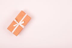 Boîte-cadeau simple décoré du ruban blanc d'arc sur le fond rose en pastel Configuration plate photographie stock libre de droits Boîte-cadeau simple décoré du ruban blanc d'arc sur le fond rose en pastel Configuration plate photographie stock libre de droits