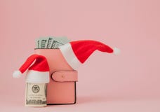Bożenarodzeniowi koszty Różowa rzemienna kiesa z Santa Claus nakrętką, prezentem, jedlinowym drzewem i dolarami banknotów na różo obraz stock Bożenarodzeniowi koszty Różowa rzemienna kiesa z Santa Claus nakrętką, prezentem, jedlinowym drzewem i dolarami banknotów na różo obraz stock