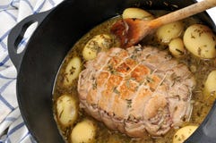 Braadstukkalfsvlees en aardappels in saus die in een gietijzerbraadpan sudderen stock afbeeldingen Braadstukkalfsvlees en aardappels in saus die in een gietijzerbraadpan sudderen stock afbeeldingen