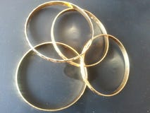 Bracelets d'or d'or sur le fond gris images stock Bracelets d'or d'or sur le fond gris images stock