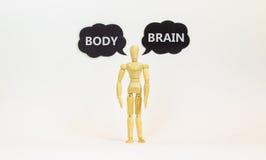 Brain or body symbol. Wooden model of businessman human. Black paper with words `brain body`. Beautiful white background, copy